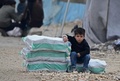 トルコとの国境近くにあるシリア北部の町の避難民キャンプで、人道支援物資のそばに座る男児（2020年2月21日撮影、資料写真）。(c)Rami al SAYED / AFP