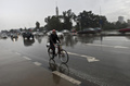 突然の寒波に見舞われたエジプトの首都カイロ（Cairo）で、雨の中を自転車に乗る男性。郊外ではここ数年で初めての降雪が観測された（2013年12月13日撮影）。(c)AFP/KHALED DESOUKI