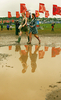 2007年6月22日、サマセット（Somerset）のピルトン（Pilton）で開催されている「グラストンベリー・フェスティバル（Glastonbury Festival）」で泥の上を歩く来場者。(c)AFP/CARL DE SOUZA