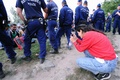 ハンガリー南部で、ロスケの移民集合場所から規制線を突破し、警官に囲まれる難民の写真を撮る女性（2015年9月8日撮影）。(c)AFP/ATTILA KISBENEDEK
