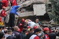 トルコのイズミルで、地震により倒壊した建物から負傷者を運び出す人々（2020年10月30日撮影）。(c)IHLAS NEWS AGENCY / AFP