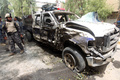 イラクの首都バグダッド（Baghdad）で起きた自動車爆弾攻撃の現場で、損傷した車を調べる警察官（2013年5月30日撮影）。(c)AFP/AHMAD AL-RUBAYE