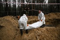ウクライナ・イジューム近郊の森で見つかった遺体を搬送する当局者（2022年9月16日撮影）。(c)Juan BARRETO / AFP