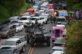 フィリピン南部ミンダナオ島のマラウィ市で、住宅街から逃れる車両で渋滞する道路を移動する装甲兵員輸送車（2017年5月25日撮影）。(c)AFP/TED ALJIBE