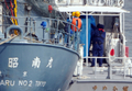 日本の調査捕鯨船団の監視船「第2昭南丸（Shonan Maru II、左）」から海上保安庁の「ゆめかぜ（Yumekaze、右）」に引き渡されるシー・シェパードの超高速抗議船アディ・ギル（Ady Gil）号船長のピーター・ベスーン（Peter Bethune）容疑者（青いシートの中）。（2010年3月12日撮影）(c)AFP/TOSHIFUMI KITAMURA