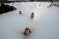 写真はアイスランドの首都レイキャビク（Reykjavik）郊外にある温泉｢ブルーラグーン（Blue Lagoon）｣を楽しむ観光客。ブルーラグーンは水の色が青と緑であることから、この名で呼ばれている。健康効果もうたわれている（2009年4月26日撮影）。(c)AFP/OLIVIER MORIN