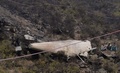 パキスタン北部カイパル・パクトゥンクワ州で、墜落したパキスタン航空機の残骸そばに座り込む人々（2016年12月8日撮影）。(c)AFP/AAMIR QURESHI