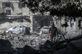 イスラエル軍による人質救出作戦で損傷した建物と散乱したがれきの中を移動する男性。パレスチナ自治区ガザ地区中部ヌセイラット避難民キャンプで（2024年6月8日撮影）。(c)EYAD BABA / AFP