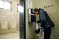中国・北京の観光名所「天壇（てんだん）」の公衆トイレに導入された、顔認証システムを取り入れたトイレットペーパーの配布装置を利用する男性（2017年3月21日撮影）。(c)AFP/WANG Zhao