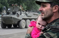 グルジア・南オセチア（South Ossetia）自治州のDzhavaで、子どもを抱き軍車両を見つめる同自治州の兵士（2008年8月10日撮影）。(c)AFP/DMITRY KOSTYUKOV