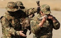 アルメニアの首都エレバン（Yerevan）郊外で開催されたアルメニア軍偵察部隊の結成記念日の祝賀行事で、生魚を食べるパフォーマンスを披露する兵士と、動物の生肉を準備して次の順番を待つ兵士（2013年11月5日撮影）。(c)AFP/KAREN MINASYAN