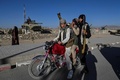 装甲車の残がいの近くでバイクにまたがるタリバン戦闘員。アフガニスタン東部ガズニ州で（2021年11月13日撮影）。(c)Hector RETAMAL / AFP