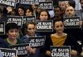 仏パリ（Paris）にあるAFP編集部で、「私はシャルリー」と書かれたプラカードを掲げ、週刊紙シャルリー・エブド（Charlie Hebdo）本社への襲撃での犠牲者に黙とうをささげるジャーナリストたち（2015年1月7日撮影）。(c)AFP/BERTRAND GUAY