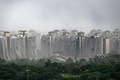 インド・ニューデリー郊外のノイダで爆破解体された超高層住宅「ツインタワーズ」のがれきと覆いが取り付けられた近隣のビル（2022年8月28日撮影）。(c)Sajjad HUSSAIN / AFP