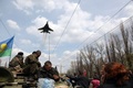 ウクライナ東部クラマトルスク（Kramatorsk）で、装甲車を取り囲む親ロシア派の活動家らの上空を飛ぶウクライナ軍の戦闘機（2014年4月16日撮影）。(c)AFP/ANATOLIY STEPANOV
