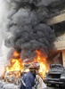 レバノン・ベイルート（Beirut）南部のハレト・フレイク（Haret Hreik）で、自動車爆弾が爆発した現場で炎を上げる車の消火に当たる消防隊員（2014年1月21日撮影）。(c)AFP