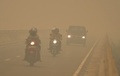 インドネシア・中カリマンタン州トゥンバンヌサで、濃い煙霧に覆われる中で通勤する人々（2015年10月25日撮影）。(c)AFP/Bay ISMOYO