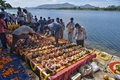 インド南部カルナタカ州のカーベリ河岸で、新型コロナウイルスで亡くなった人の遺骨が入った引き取り手のない骨つぼを置くヒンズー教の僧侶と公務員（2021年6月2日撮影）。(c)Manjunath Kiran / AFP