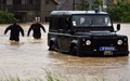 セルビア・ベオグラード（Belgrade）の南約45キロのラザレバツ（Lazarevac）で、冠水した道路を進む警察官（2014年5月15日撮影）。(c)AFP/ANDREJ ISAKOVIC