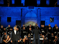イタリア・ローマ（Rome）の古代遺跡コロッセオ（Colosseum）で25日、オペラ歌手アンドレア・ボチェッリ（Andrea Bocelli）が同国アブルツォ（Abruzzo）州の交響楽団とともに、チャリティーコンサートを開催した。このコンサートは、4月のイタリア中部地震で被害を受けた音楽学校の再建を目的に行われた。会場に入ることのできた観客は、わずか380人だった。写真は、ステージで歌声を披露するボチェッリ（左、2009年5月25日撮影）。(c)AFP/TIZIANA FABI