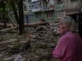 早朝、ロシア軍の攻撃で破壊された建物の外に立つ住民。ウクライナ東部ドネツク州コンスタンチノフカで（2022年8月6日撮影）。(c)Bulent KILIC / AFP