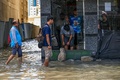アラブ首長国連邦（UAE）シャルジャの冠水した道路を歩く人々（2024年4月17日撮影）。(c)Ahmed RAMAZAN / AFP