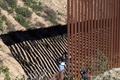 メキシコ・バハカリフォルニア州ティフアナで、国境フェンスを越える中米移民（2018年12月30日撮影）。(c)GUILLERMO ARIAS / AFP