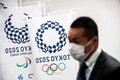 都内で開かれた東京五輪関連の記者会見で、マスクをして五輪のロゴの前に立つ記者（2020年3月11日撮影）。(c)Behrouz MEHRI / AFP