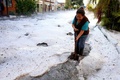 メキシコ・ハリスコ州グアダラハラで、道路に積もったひょうを取り除こうとする女性（2019年6月30日撮影）。(c)Ulises RUIZ / AFP