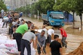 中国・江西省九江で、冠水した道沿いに堤防を築く人々（2020年7月13日撮影）。(c)STR / AFP 