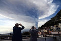 イタリア・シチリア島の町、タオルミーナ上空に上がったエトナ山の噴煙を撮影する人々（2015年12月4日撮影）。(c)AFP/GIOVANNI ISOLINO