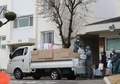 韓国・大邱で、封鎖された複合住宅に防護服を着用して物資を運び入れる保健当局者（2020年3月7日撮影）。(c)YONHAP/AFP