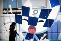 東京五輪の大会マスコット、ミライトワの絵の前を通る人（2021年1月22日撮影）。(c)Behrouz MEHRI / AFP