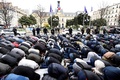 フランス・パリ近郊クリシーの市庁舎前の路上で、地元当局に無許可の礼拝所を閉鎖されたことに抗議して礼拝を行うイスラム教徒らと、その横に立つ機動隊員（2017年3月24日撮影）。(c)AFP/BERTRAND GUAY