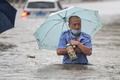 中国・河南省鄭州市で、冠水した道路を歩く人（2021年7月20日撮影）。(c)STR / AFP