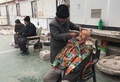中国新疆ウイグル自治区カシュガルで、モスク（イスラム礼拝所）前で理髪師にひげなどをそってもらう男性（2018年2月18日撮影）。(c)BEN DOOLEY / AFP