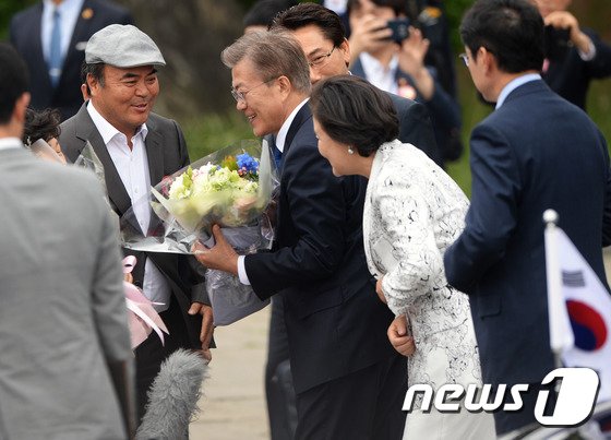 2017年5月10日、大統領府噴水台前で開かれた歓迎行事で、住民から花束を受け取る文在寅大統領夫妻(c)news1
