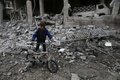 シリア政府軍とロシア軍によるものとされる爆撃があったシリア首都ダマスカス近郊の東グータで、がれきの中を自転車を押しながら歩く男の子（2018年1月6日撮影）。(c)AFP PHOTO / ABDULMONAM EASSA