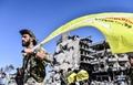 シリア北部ラッカで、クルド人とアラブ人の合同部隊「シリア民主軍」の旗を手にする隊員（2017年10月17日撮影）。(c)AFP/BULENT KILIC