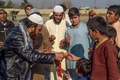パキスタン北西部ペシャワールの難民キャンプで、アフガニスタンで「暴力削減措置期間」の合意がされたことを祝福しお菓子を配る難民（2020年2月22日撮影）。(c)Abdul MAJEED / AFP