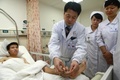 中国中部・湖南（Hunan）省長沙（Changsha）の病院で、シャオ・ウェイ（Xiao Wei）さんのかかと付近に接続された手の状態を確認する医師（中央、2013年12月4日撮影）。(c)AFP