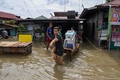 台風16号が通過した後のフィリピン・ブラカン州サンイルデフォンソで、自宅から荷物を持ち出す人（2022年9月26日撮影）。(c)TED ALJIBE / AFP