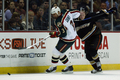 写真は、ダックスのコリー・ペリー（%%Corey Perry%%、右）のチェックを受けながらもパックを追うワイルドのキース・カーニー（%%Keith Carney%%）。(c)AFP/Getty Images Jeff Gross