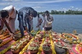 インド南部カルナタカ州のカーベリ河岸で、新型コロナウイルスで亡くなった人の遺骨が入った引き取り手のない骨つぼを並べるヒンズー教の僧侶と公務員（2021年6月2日撮影）。(c)Manjunath Kiran / AFP