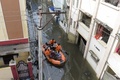 インド・ハイデラバードの豪雨で冠水した通りで、ボートを使って住民を避難させる国家災害対応部隊の隊員ら（2020年10月15日撮影）。(c)NOAH SEELAM / AFP