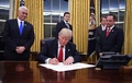 米首都ワシントンのホワイトハウスで、マイク・ペンス副大統領（左）とラインス・プリーバス首席補佐官（右）に見守られながら大統領令に署名するドナルド・トランプ大統領（2017年1月20日撮影）。(c)AFP/JIM WATSON