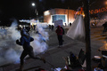 米ミズーリ（Missouri）州ファーガソン（Ferguson）で、警察が使用した催涙ガスから逃げる、黒人青年の射殺事件に抗議するデモに参加する人々（2014年11月24日撮影）。(c)AFP/Jewel Samad