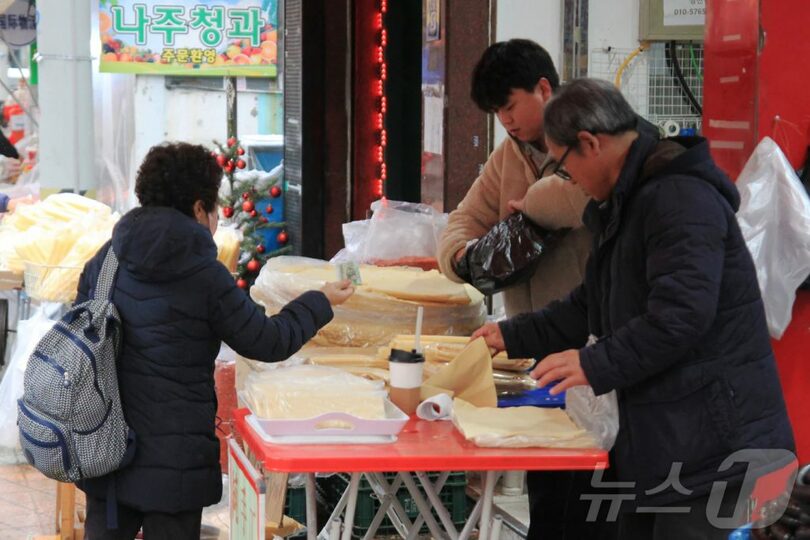 27日午後、大林中央市場で、ある女性が商人から干し豆腐を購入している(c)news1