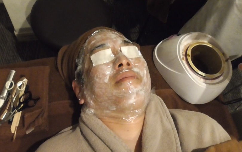 目の部分を脱脂綿で保護し、鼻の穴と唇を除く顔全体をラップで覆って栄養を沈着させるプロセス(c)KOREA WAVE