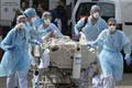 フランス東部ミュルーズの病院で、別の病院へ移送する患者をドクターヘリに乗せるため移動させる医療スタッフ（2020年3月22日撮影）。(c)SEBASTIEN BOZON / AFP